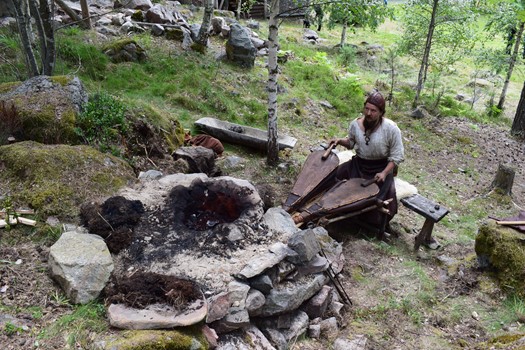 person i medeltida kläder vid eldstad
