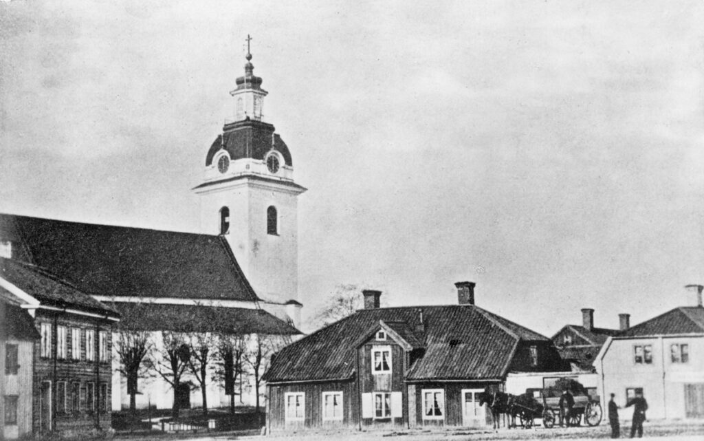 Heliga Trefaldighets kyrka med några låga trähus framför.