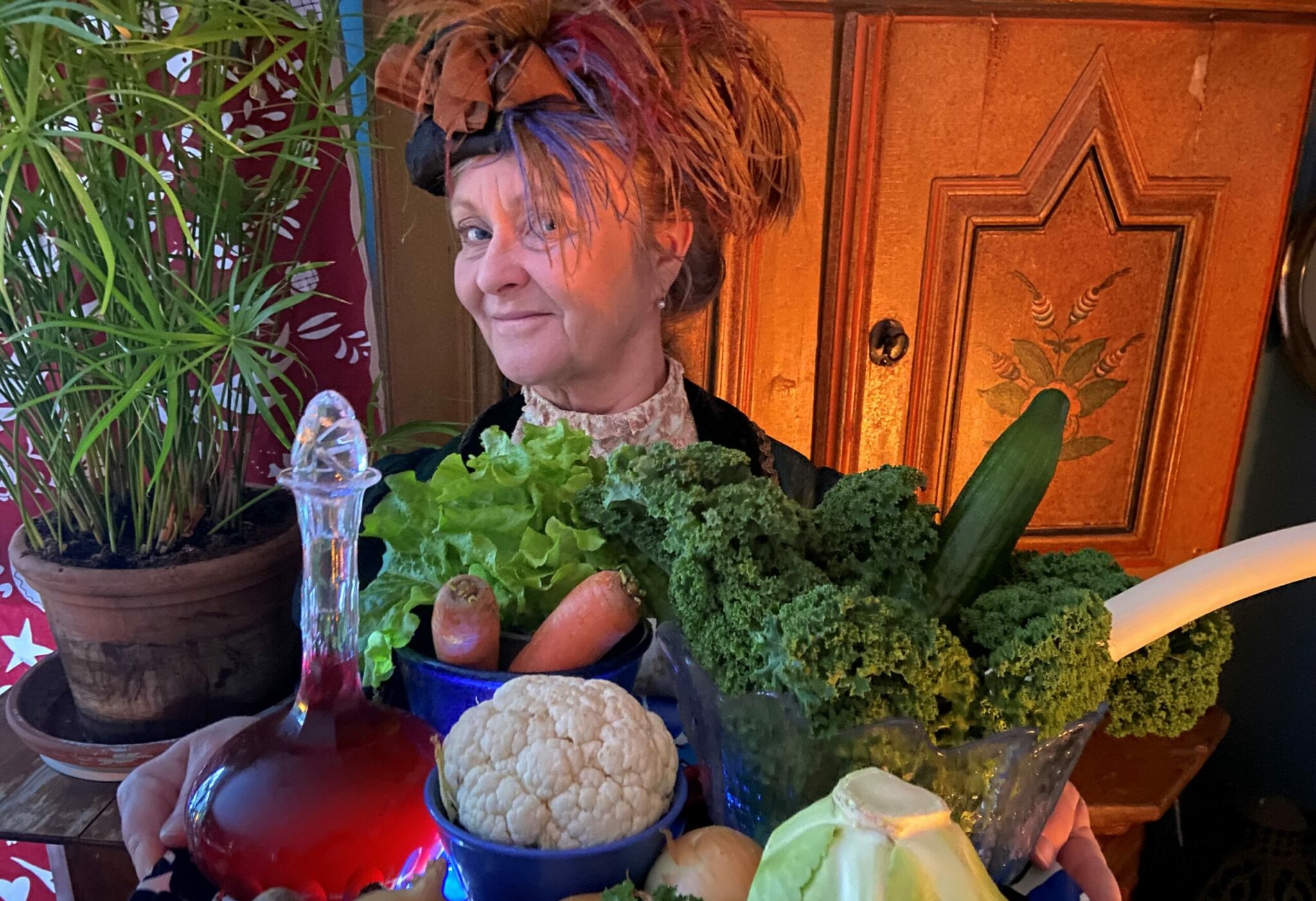 En leende kvinna bakom en massa grönsaker.