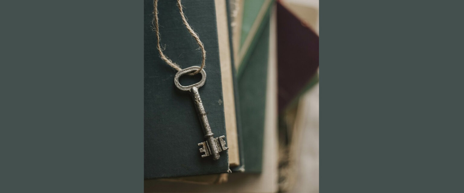 En nyckel sittande på ett snöre. Nyckeln ligger på en trave böcker..