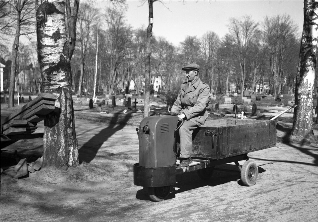 Ett svartvitt foto på en man som kör en liten tryck på Gamla kyrkogården.